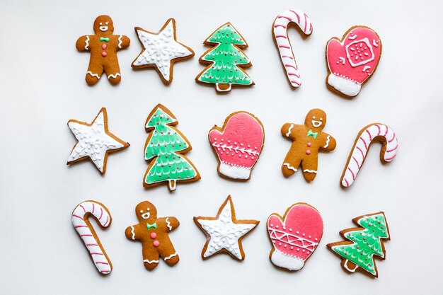 Galletas de jengibre festivas hechas a mano en forma de estrellas copos de nieve personas calcetines personal mitones árboles de Navidad corazones para Navidad y vacaciones de año nuevo sobre fondo de papel blanco