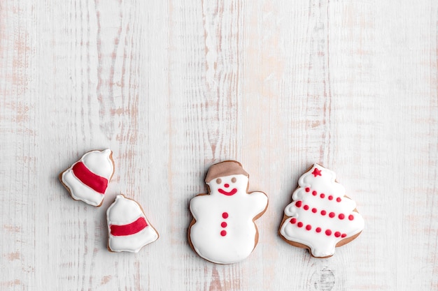 Galletas de jengibre en forma de árbol de navidad, muñeco de nieve y timbre sobre un fondo de madera con textura brillante