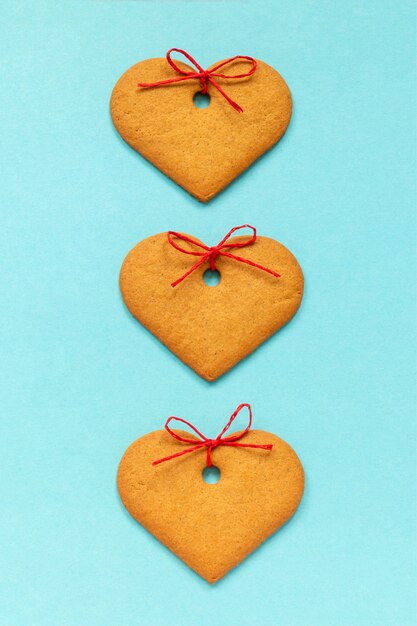 Galletas de jengibre en forma de corazón decoradas con un lazo sobre fondo azul