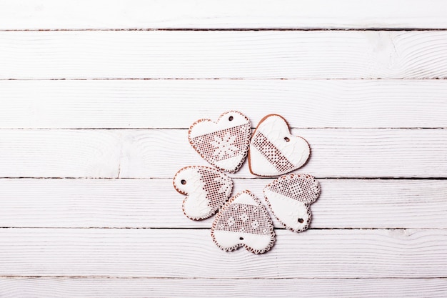 Galletas de jengibre en forma de corazón con glaseado sobre un fondo de madera