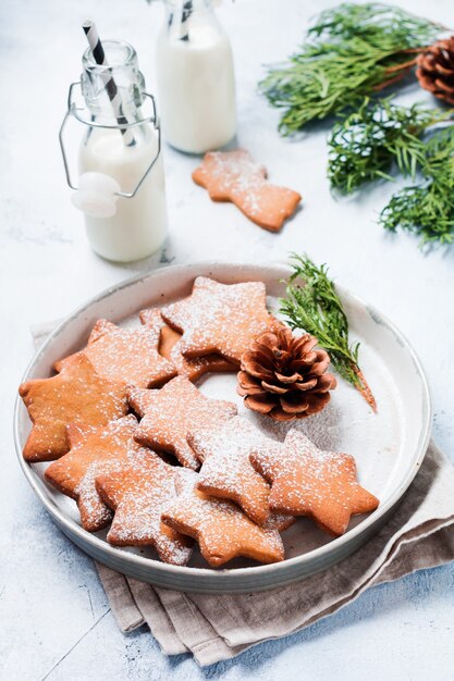 Galletas de jengibre de forma de estrella de Navidad caseras en placa de cerámica sobre superficie gris de hormigón viejo. Vista superior