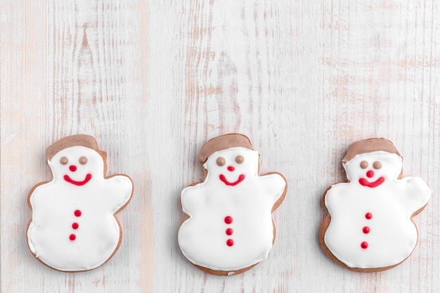 Galletas de jengibre en forma de muñeco de nieve sobre un fondo de madera con textura brillante