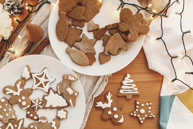 Galletas de jengibre con glaseado en mesa de madera con luces festivas tiempo atmosférico Lay Flat