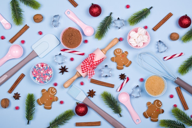 Galletas de jengibre con ingredientes para hornear y utensilios de cocina navideños