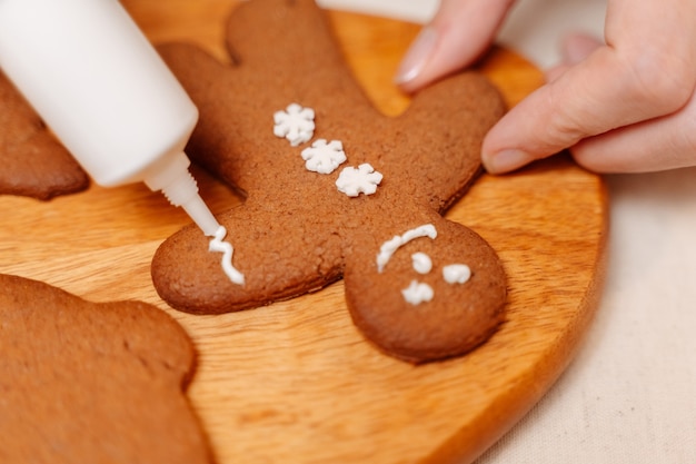 Las galletas de jengibre navideñas en forma de hombre están decoradas con esmalte blanco sobre una tabla de madera