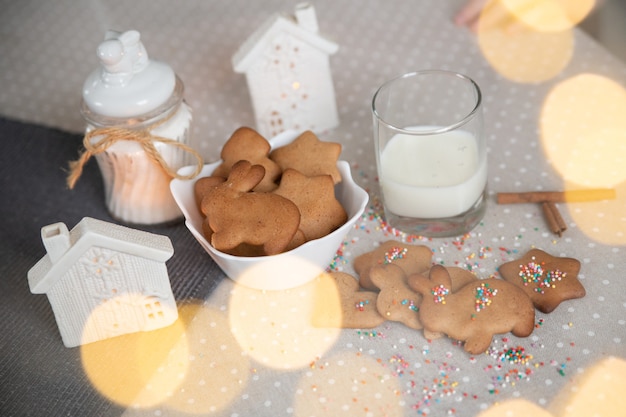 Galletas de jengibre navideñas con leche en una mesa brillante