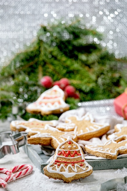 Galletas de jengibre navideñas tradicionales caseras con glaseado adornado. Hombre de pan de jengibre, ángel, campana con adornos navideños sobre superficie blanca bokeh.