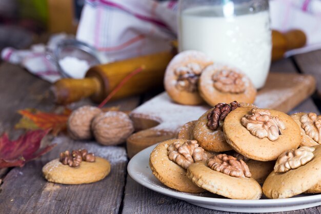 Galletas de jengibre con nueces sobre una mesa y una taza de leche