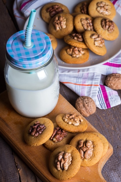 Galletas de jengibre con nueces sobre una mesa y una taza de leche