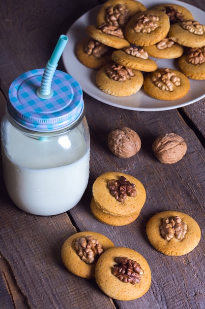 Galletas de jengibre con nueces sobre una mesa y una taza de leche