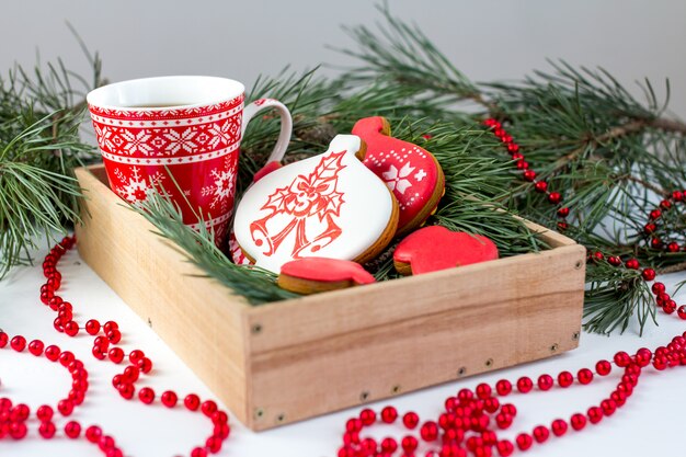 Galletas de jengibre y una taza de té sobre la mesa con ramas de abeto