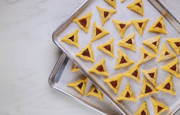 Galletas judías crudas con mermelada en la bandeja del horno.