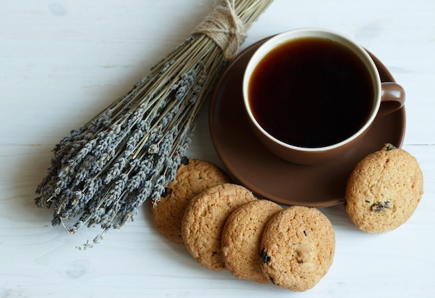 Galletas de lavanda y taza de té sobre fondo blanco de madera