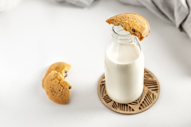 Galletas y leche en una botella sobre una mesa blanca con una servilleta