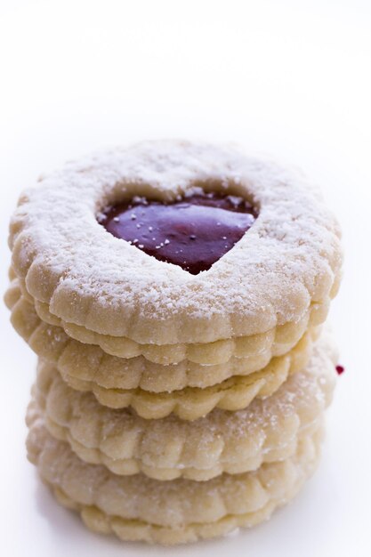 Galletas Linzer Torte sobre fondo blanco con azúcar en polvo espolvoreado en la parte superior.