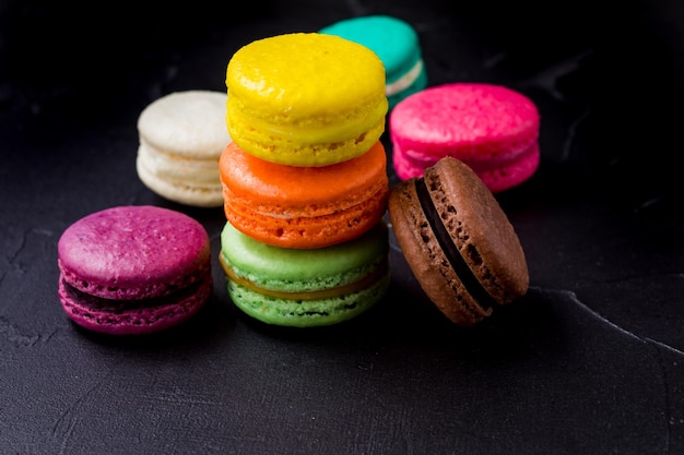 Galletas macarons de colores en el fondo negro