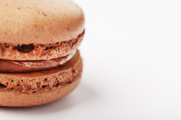 Foto galletas de macarrones con chocolate sobre un fondo blanco con relleno marrón, aislado.