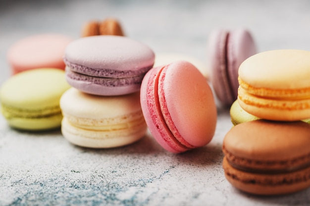 Galletas de macarrones de diferentes colores en una caja sobre un fondo gris con textura de piedra Espacio libre.