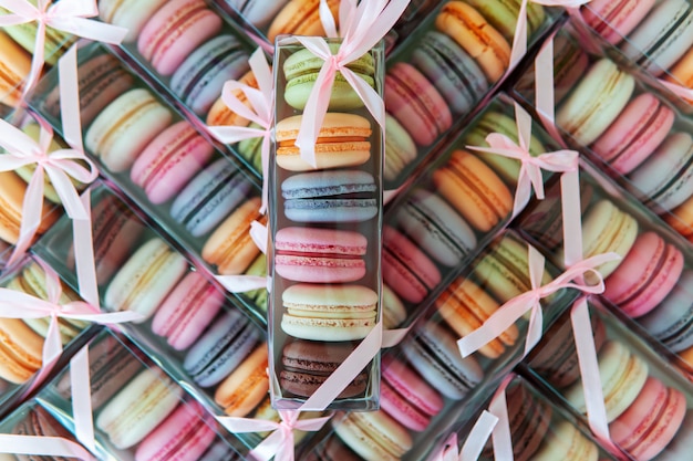 Galletas de macarrones de diferentes colores en un paquete con un lazo, muchas cajas con galletas en forma de textura.