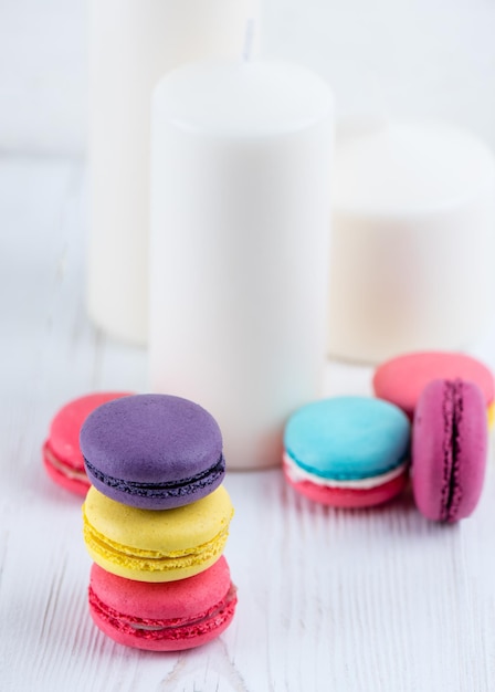 Galletas de macarrones dulces y coloridas sobre un fondo de velas