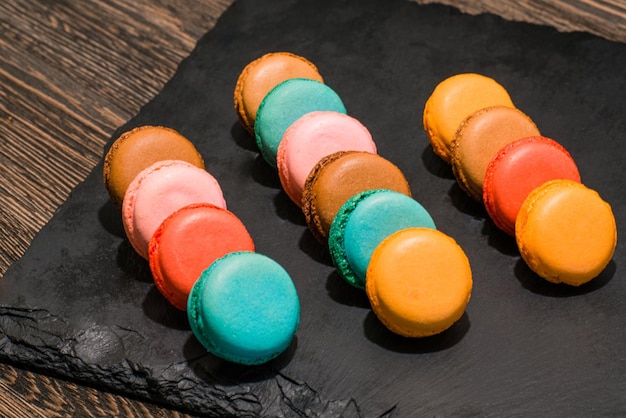 Las galletas macarrones francesas multicolores sobre una piedra negra