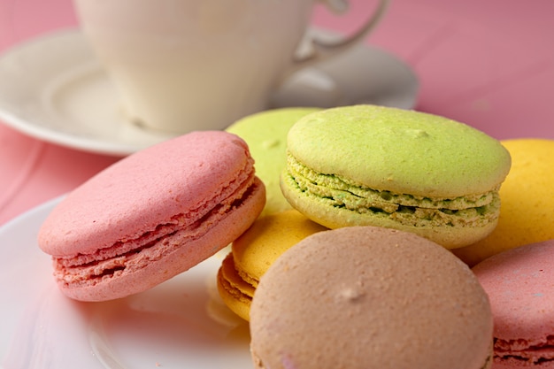 Galletas de macarrones franceses de colores brillantes servidos en plato de cerámica blanca