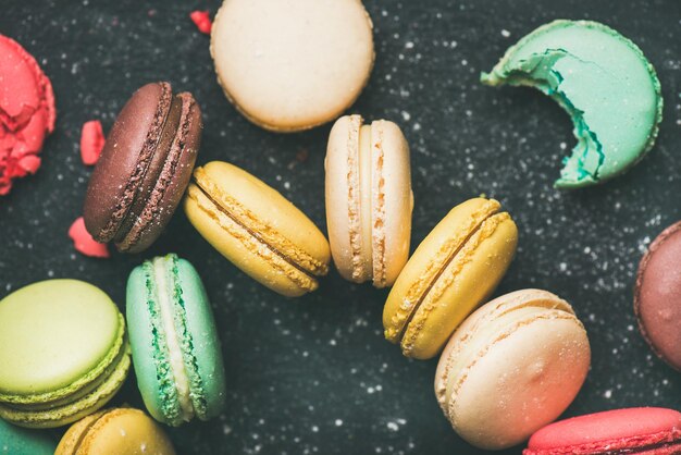 Galletas de macarrones franceses de colores dulces sobre fondo negro vista superior