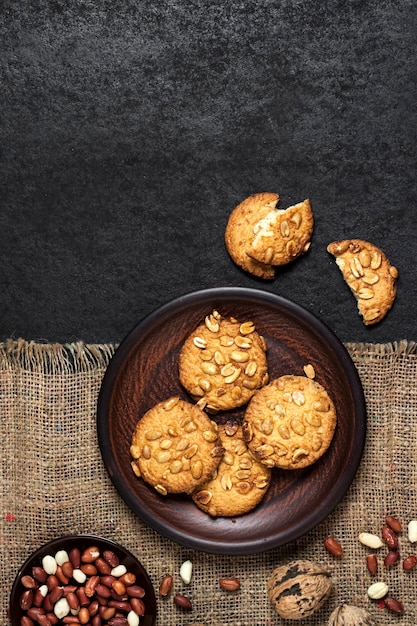 Galletas de maní caseras en una placa marrón con maní crudo en segundo plano.