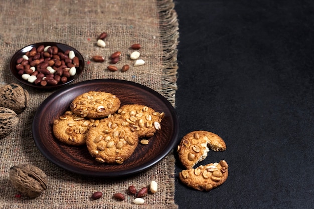 Galletas de maní caseras en un plato marrón con maní crudo en superficie