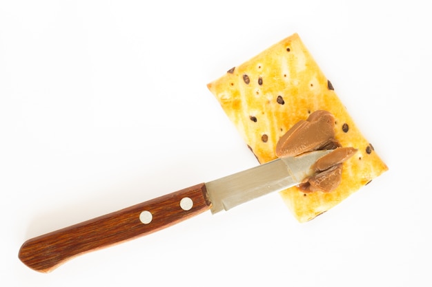 Foto galletas, mantequilla de chocolate y un cuchillo. fondo blanco