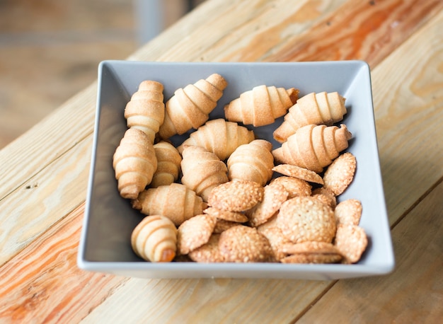 Galletas de mantequilla en forma de bagels en una placa gris sobre una mesa de madera