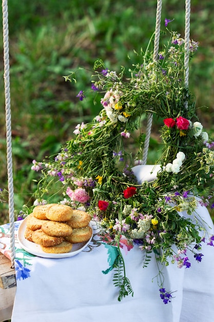 Galletas de mantequilla con queso azul y semillas de sésamo y una corona de flores silvestres en un columpio.