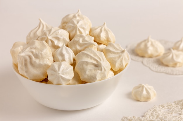 Galletas de merengue francés en un recipiente sobre fondo blanco.