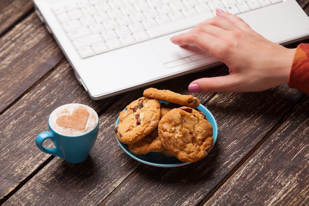 Foto galletas y mujeres de la mano con el cuaderno.