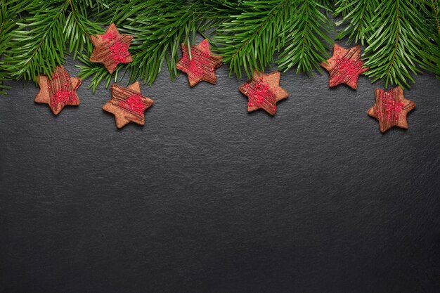 Foto galletas de navidad caseras estrellas de chocolate con crujidos de frambuesa en mesa de pizarra con ramas de pino