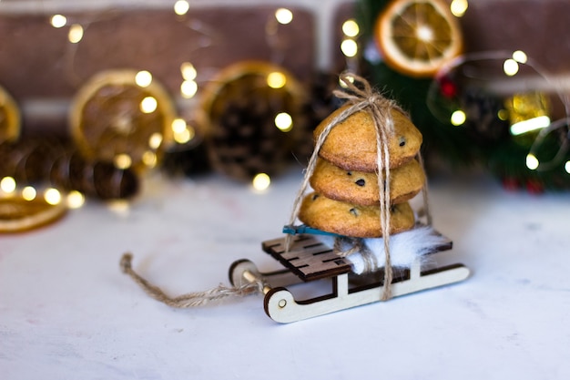 Galletas de Navidad con chocolate en trineos con el telón de fondo de guirnaldas y ramas de abeto