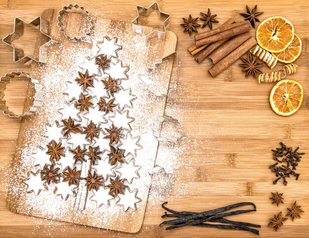 Foto galletas de navidad estrellas de canela y especias sobre fondo de madera. vainas de vainilla, clavo, anís estrellado y canela