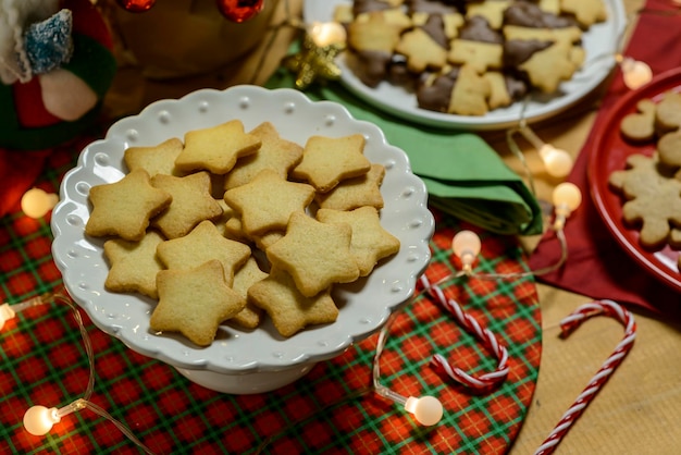Foto galletas de navidad y luces sobre fondo blanco de madera