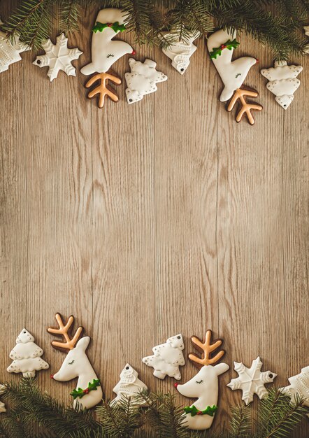 Foto galletas de navidad y rama de pino en mesa de madera