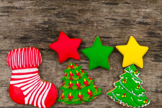 Galletas navideñas navideñas en forma de árbol de Navidad, estrella y calcetín navideño. Deliciosos panes de jengibre en la mesa de madera rústica. Vista superior