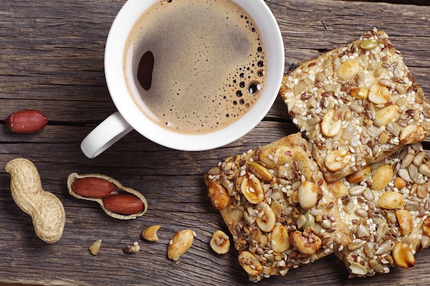 Galletas con nueces y café Galletas con nueces, semillas y taza de café en la mesa de madera antigua, vista superior