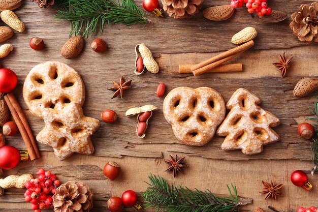 Galletas con nueces, especias y ramitas de árbol de Navidad sobre superficie de madera rústica