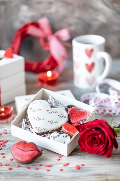 Galletas o galletas de jengibre en una caja de regalo con una cinta roja sobre una mesa de madera. Día de San Valentín.