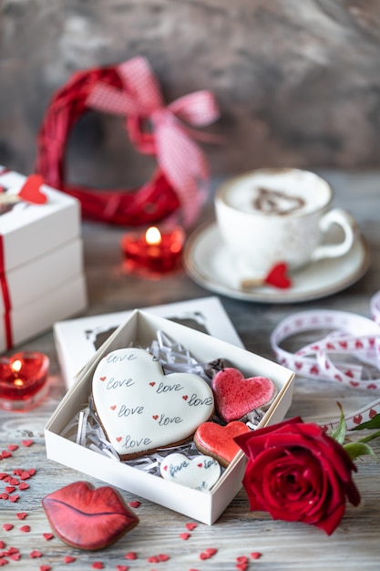 Galletas o galletas de jengibre en una caja de regalo con una cinta roja sobre una mesa de madera.