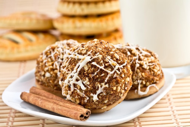 Galletas y palitos de canela en un plato y un vaso de leche al fondo