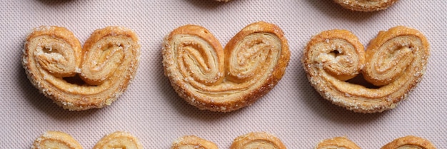 Galletas palmier u orejas de hojaldre en bandeja de galletas en forma de corazón vista superior primer plano