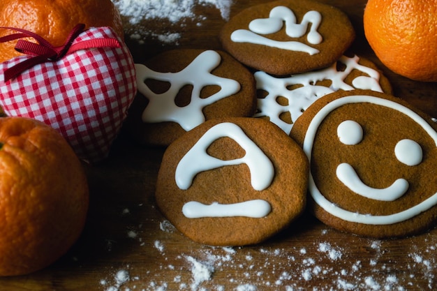 Galletas de pan de jengibre cubiertas de glaseado blanco rodeadas de mandarinas y un corazón de juguete