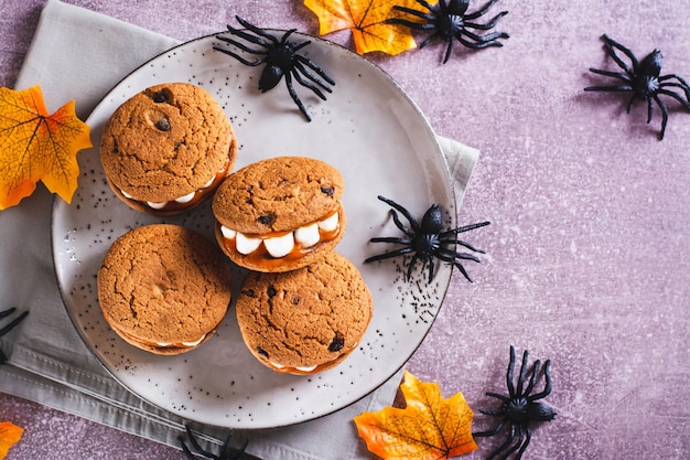 Las galletas de pan de jengibre con dientes de malvavisco en una vista superior del plato de Halloween