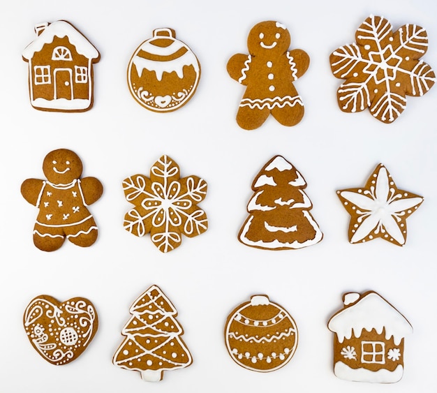 Galletas de pan de jengibre de Navidad con glaseado sobre un fondo blanco en forma de casa y hombre de pan de jengibre Árbol de Navidad y bolas estrellas y copos de nieve y corazones