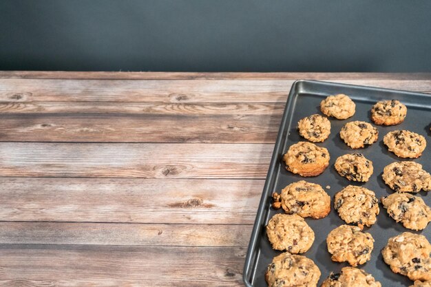 Galletas de pasas de avena masticables recién horneadas en una bandeja para hornear.